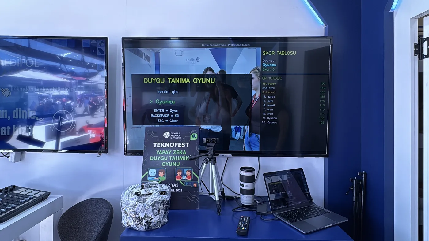 The TEKNOFEST 2025 stand: the emotion-recognition game on a large screen with name entry and a leaderboard, a webcam on a tripod and a laptop